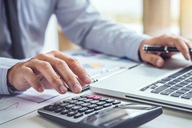 Un homme d'affaires ou comptable travaillant sur des investissements financiers, utilisant une calculatrice pour analyser les données de croissance commerciale et de marché. Des documents financiers, des graphiques et des statistiques sont visibles, illustrant une scène de comptabilité et d'analyse économique.